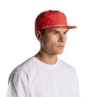 Man in a red cap and white t-shirt looking to the side against a white background.