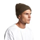 Man in a white shirt and brown knit beanie, looking to the right against a white background.