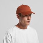Man in a white t-shirt wearing a rust-colored baseball cap against a plain background.