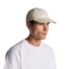 Man in a white t-shirt and beige baseball cap looking to the side against a white background.