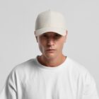 Man in a white cap and white t-shirt looking at the camera against a plain background.