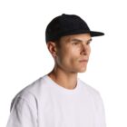 Man in white shirt and black cap looking to the side against a plain background.