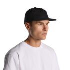 Man in white t-shirt and black cap looking to the side against a plain background.