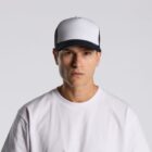 Man wearing a white t-shirt and a black-and-white trucker cap against a plain background.