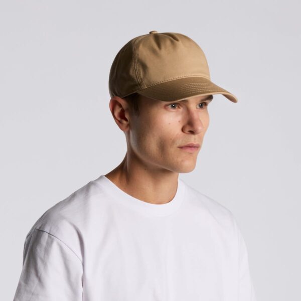 Man in a beige baseball cap and white t-shirt against a plain gray background.