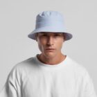 Man in a light blue bucket hat and white shirt looks directly at the camera.