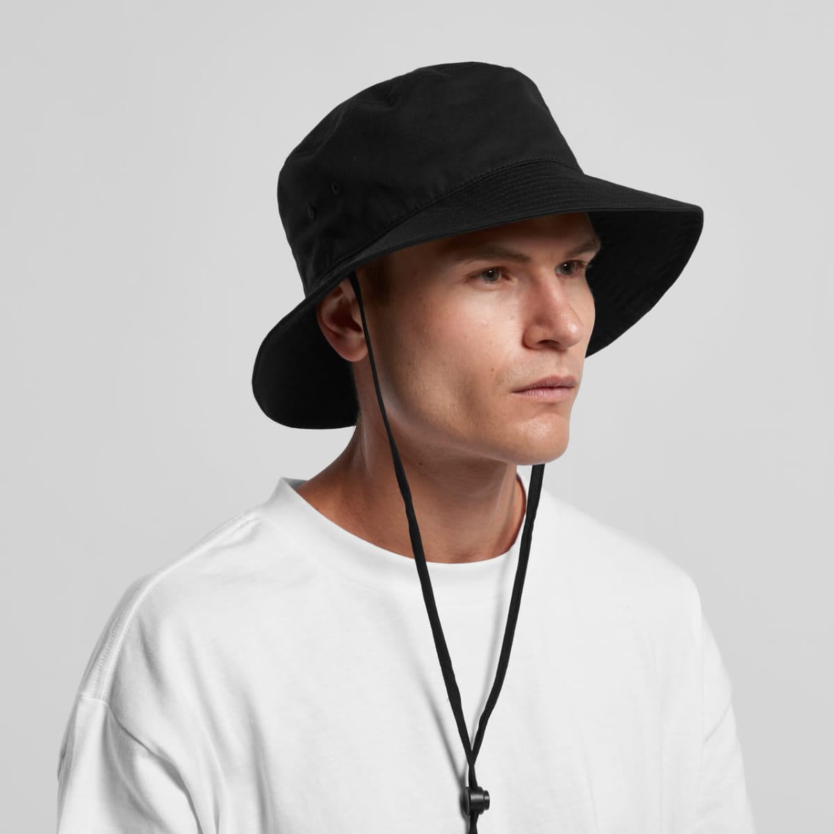 A person in a white shirt wearing a black bucket hat with chin straps.