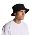 Person wearing a black bucket hat and a plain white t-shirt against a white background.