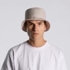 Man in a white shirt and beige bucket hat looking directly at the camera.