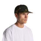 Man wearing a camouflage baseball cap and white t-shirt, looking to the side.