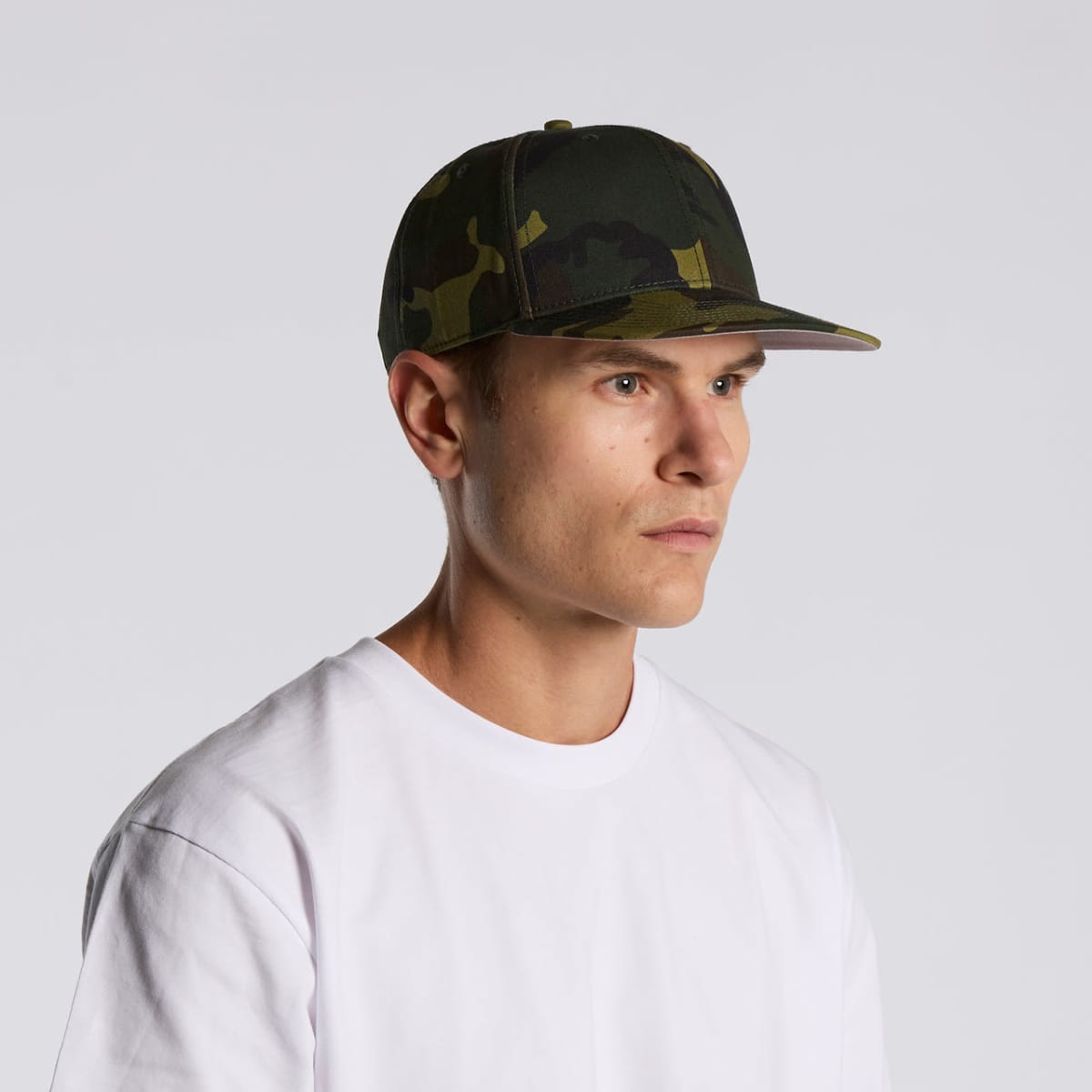Man in a white shirt wearing a green camouflage hat, looking to the side.