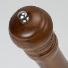 Close-up of the top of a wooden pepper grinder with a metal knob.