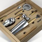 Bartender cocktail kit with metal and wood tools in a brown box.