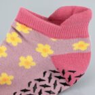 Pink and purple sock with yellow flowers and black non-slip grips on the sole.