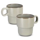 Two beige ceramic mugs with large handles and dark rims, placed side by side.