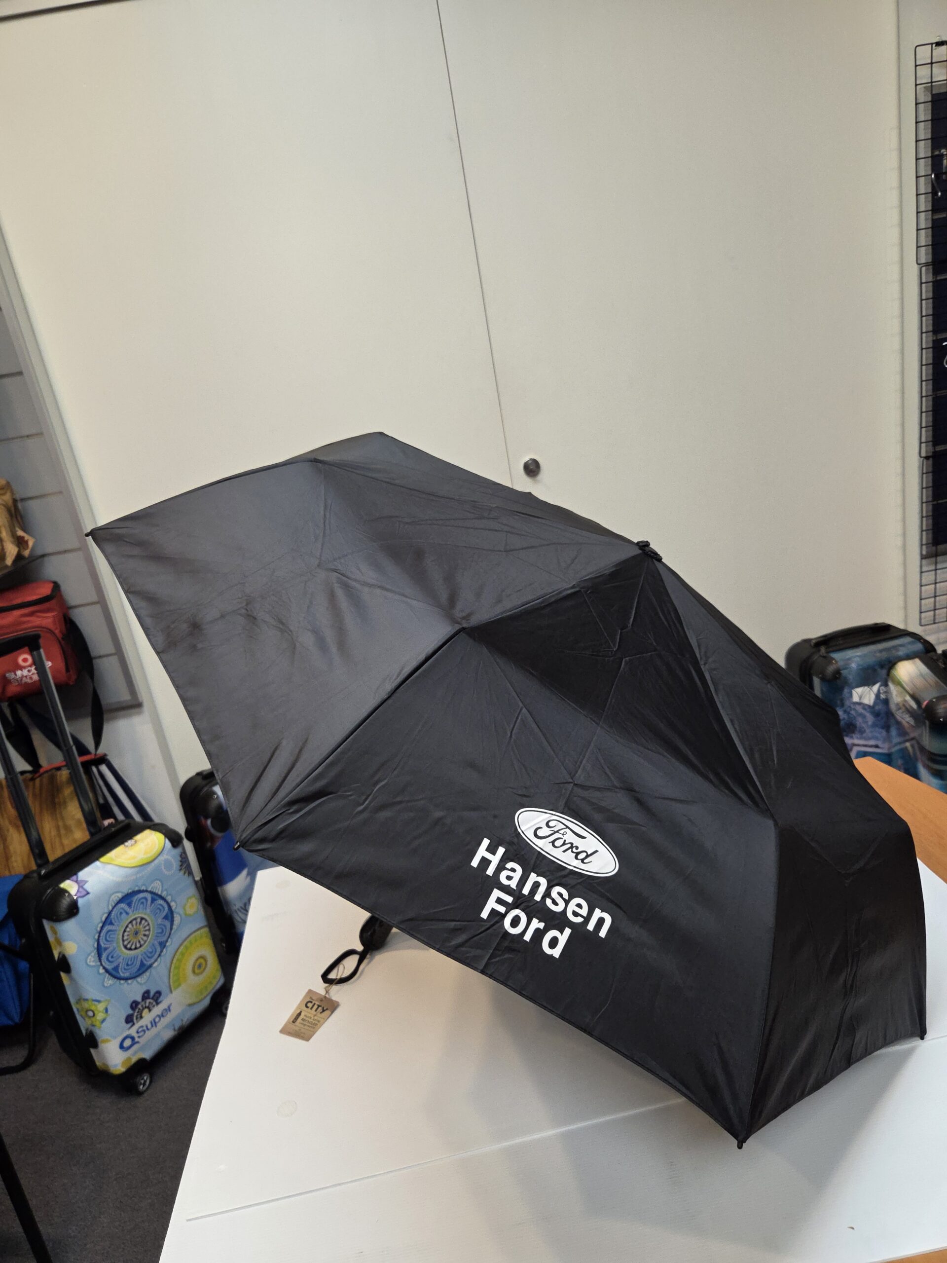 Full view of a black umbrella with white Hansen Ford print
