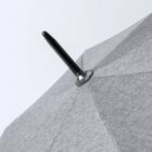 Close-up of the top of a gray fabric umbrella with a black pointed tip.