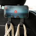Smartphone attached to a car seat headrest playing a video, with ropes hanging below.