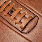 Close-up of brown leather football stitching and laces.