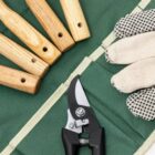 Garden tools, pruning shears, and gloves on a green fabric tool organizer.