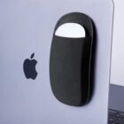 A black pouch holding a mouse is attached to a silver MacBook with an Apple logo.