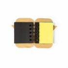 Small open notebook with black cover and yellow sticky notes on a wooden base, top view.