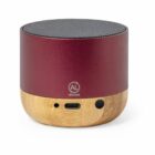 Small red and bamboo portable speaker with mesh top and charging port on the front.