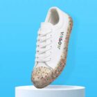 White sneaker with colorful speckled sole and Willsolly logo, floating on a blue background.