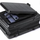 Black suitcase with an open compartment showing a laptop and a smartphone inside.