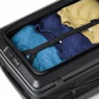 Open suitcase with folded clothes secured by a strap.