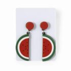 Two earrings shaped like watermelon slices on a white card.