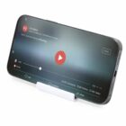 Smartphone on a stand displaying a paused video with play button and social stats.