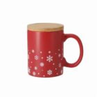 Red mug with white snowflake designs and a wooden lid, isolated on a white background.