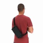 Man in red shirt wearing a black sling bag across his back, facing away from the camera.