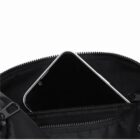 A smartphone partially inside the zippered pocket of a black bag.