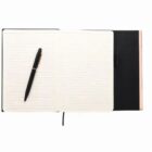 Open lined notebook with a black pen resting on its left page, against a white background.
