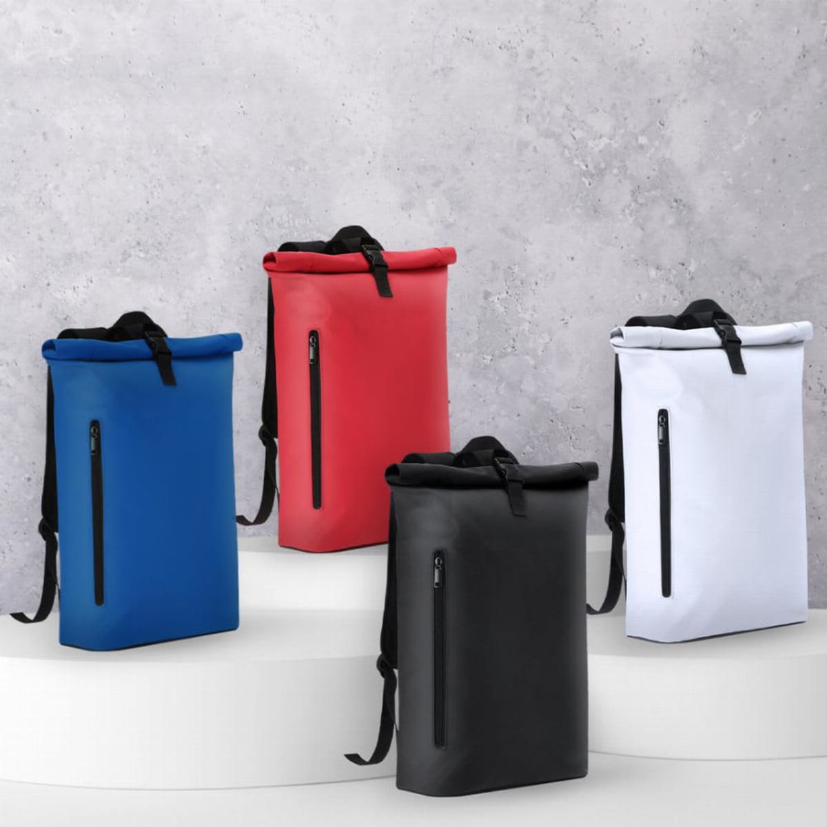 Four backpacks in blue, red, black, and white displayed on white platforms against a gray wall.