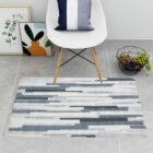 A white chair on a gray striped rug with decor, grapes, and framed art nearby.