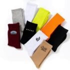 Nine pairs of colorful socks arranged in a fan, some with logos or text on them.