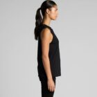 Woman in black sleeveless top and pants standing in profile against a plain background.