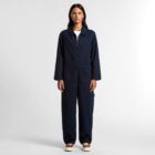 Woman in a navy blue jumpsuit standing against a plain white background.
