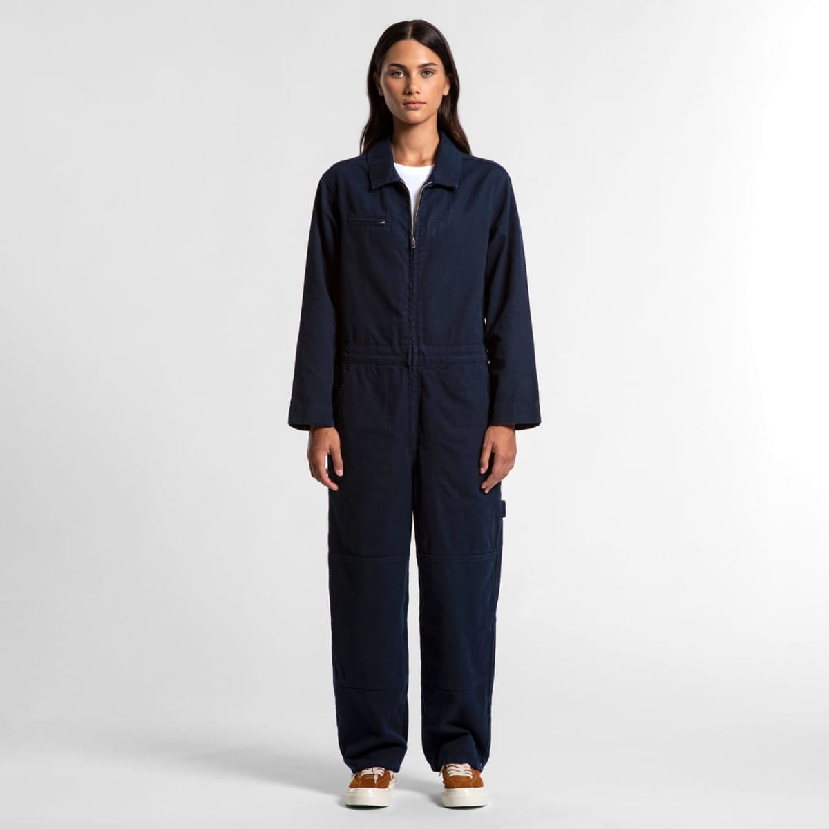 Woman in a navy blue jumpsuit standing against a plain white background.