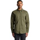 Man wearing a long-sleeve olive green button-up shirt, standing against a white background.