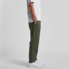 Person wearing olive green pants, white t-shirt, and white sneakers, standing sideways.