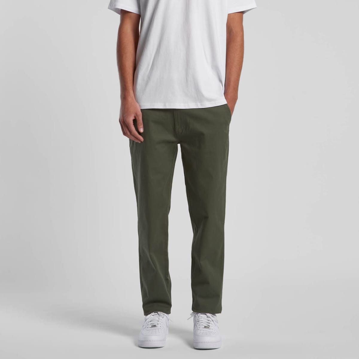 Person wearing a white t-shirt, green pants, and white sneakers, standing against a plain background.