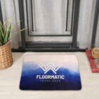 Rectangular blue gradient floor mat with FLOORMATIC YOURSLOGAN text near a plant and window.