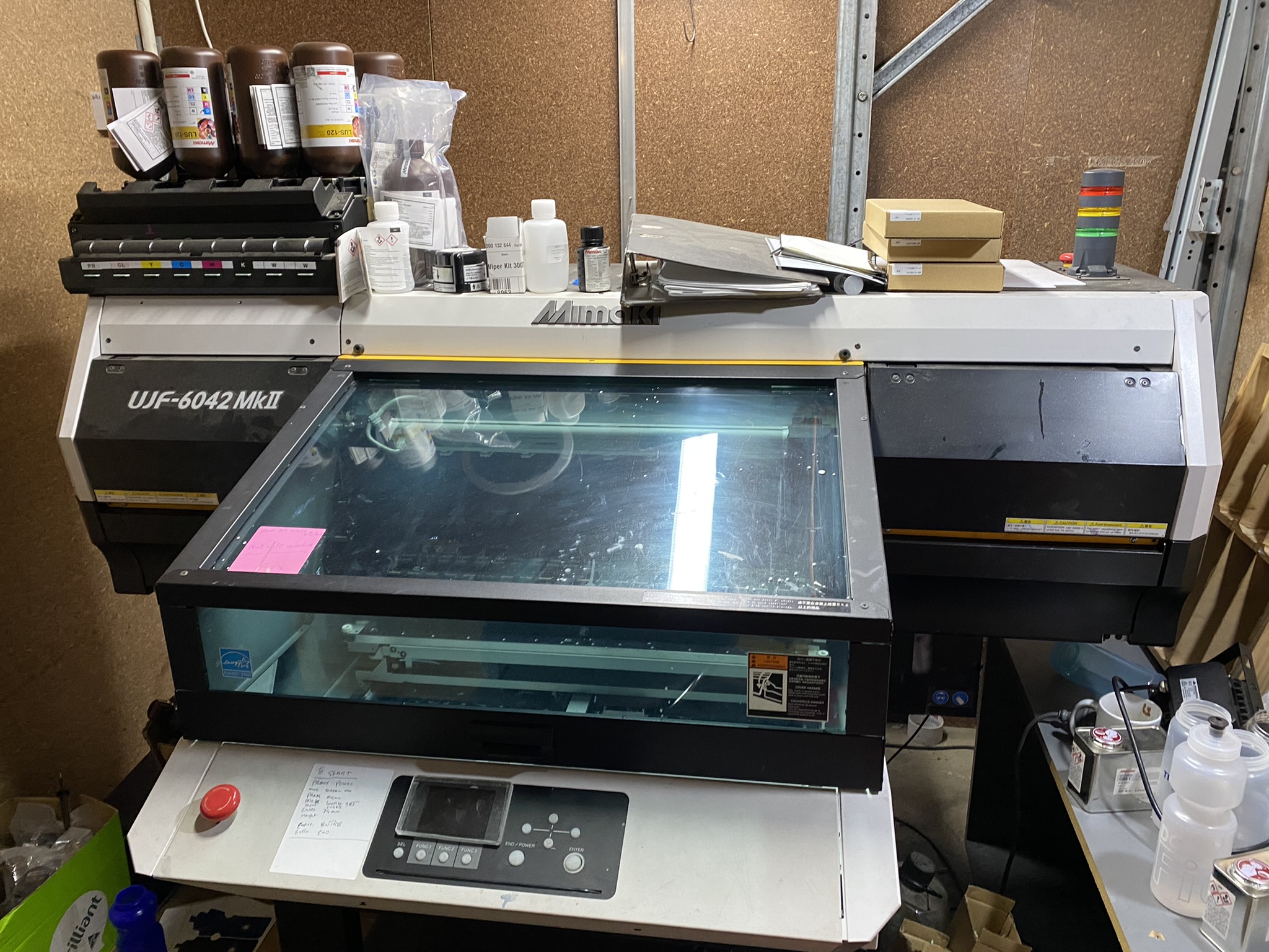 A Mimaki UJF-6042 MkII prints custom bottles in a cluttered Australian Made workspace.