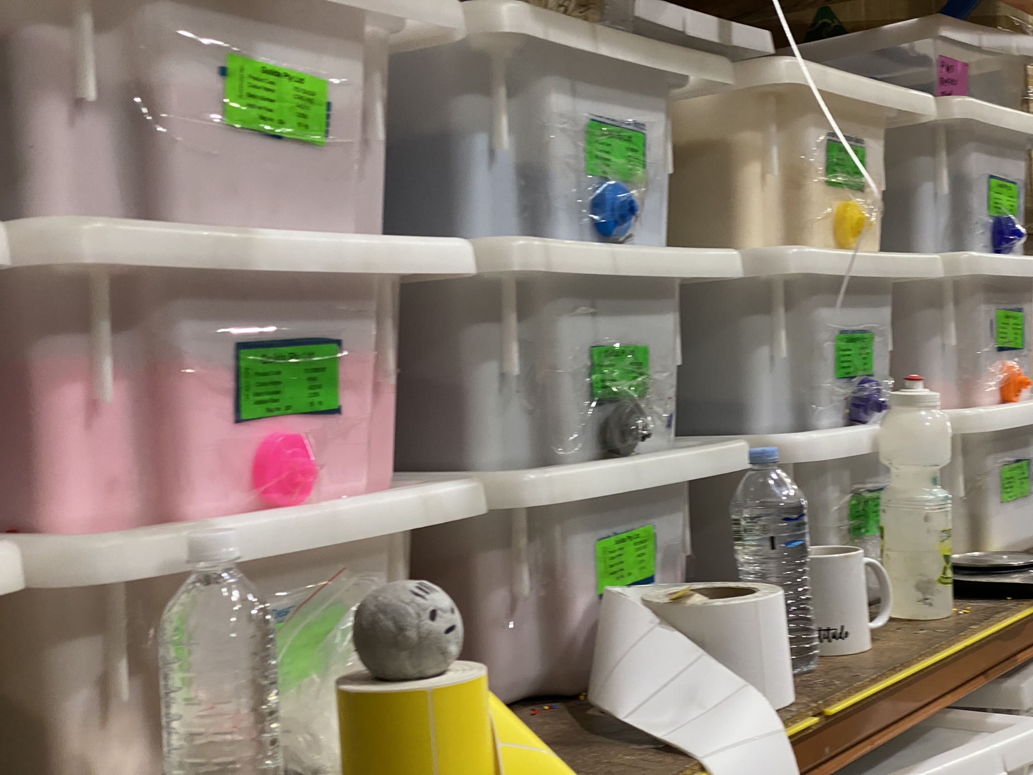 Plastic bins with labels, stacked colour resin pellets, and custom bottles made in Australia in front.