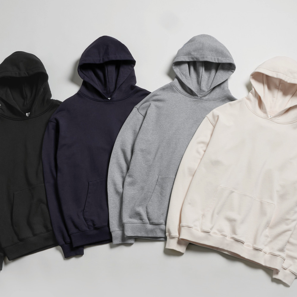 Four premium quality AS Colour hoodies in black, navy, gray, and cream on a white surface.