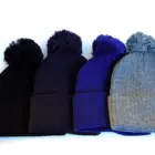 Acrylic Beanies with Pompon in black, dark blue, navy, and gray on a white background.